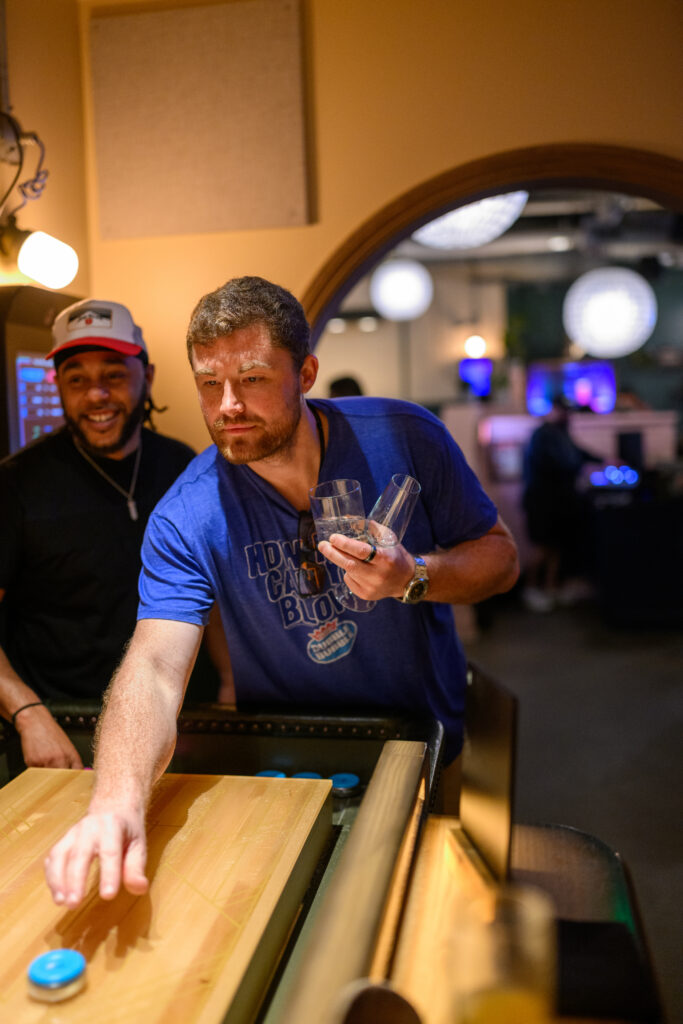 A guest playing shuffleboard at a 35th-birthday celebration at Electric Shuffle in Austin