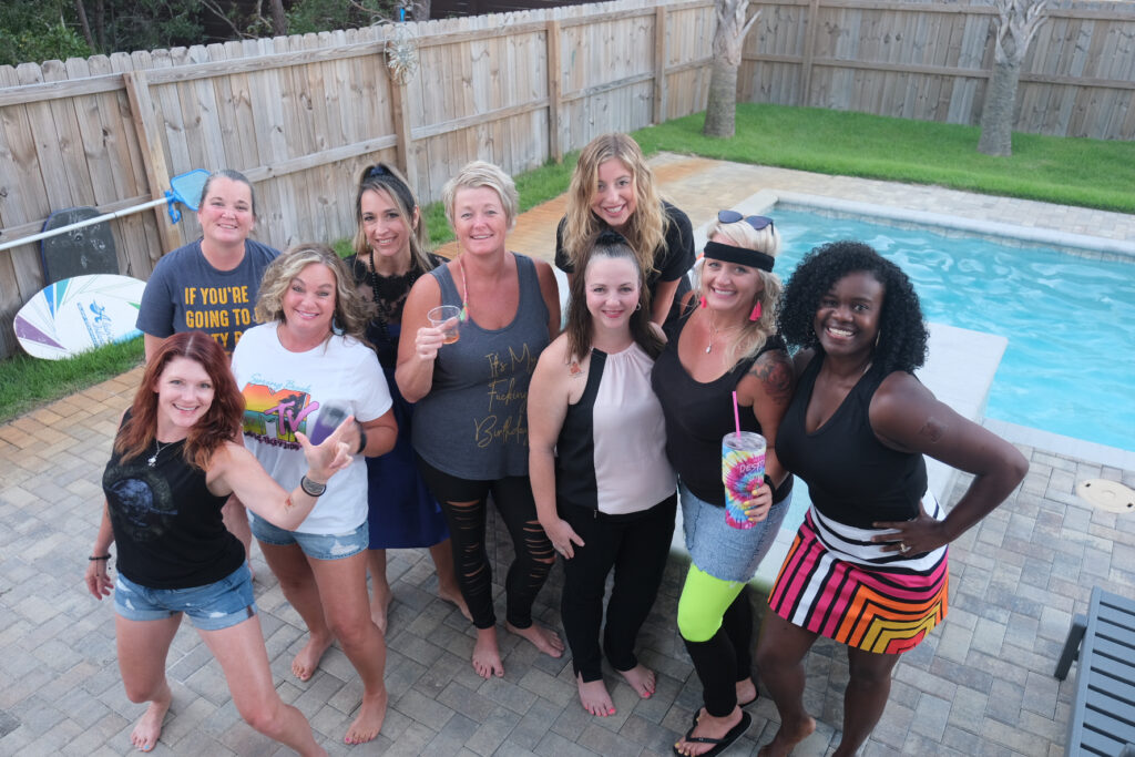 A group of friends posing at the pool deck during a backyard fiftieth birthday at golden hour